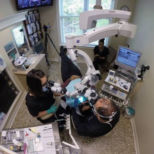 Photo of Raleigh NC Endodontist Dr Horalek and Dental Assistant, using a Surgical Operating Microscope on a patient